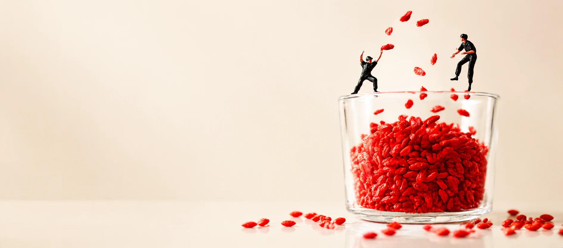 Miniature figures tossing goji berries above a glass